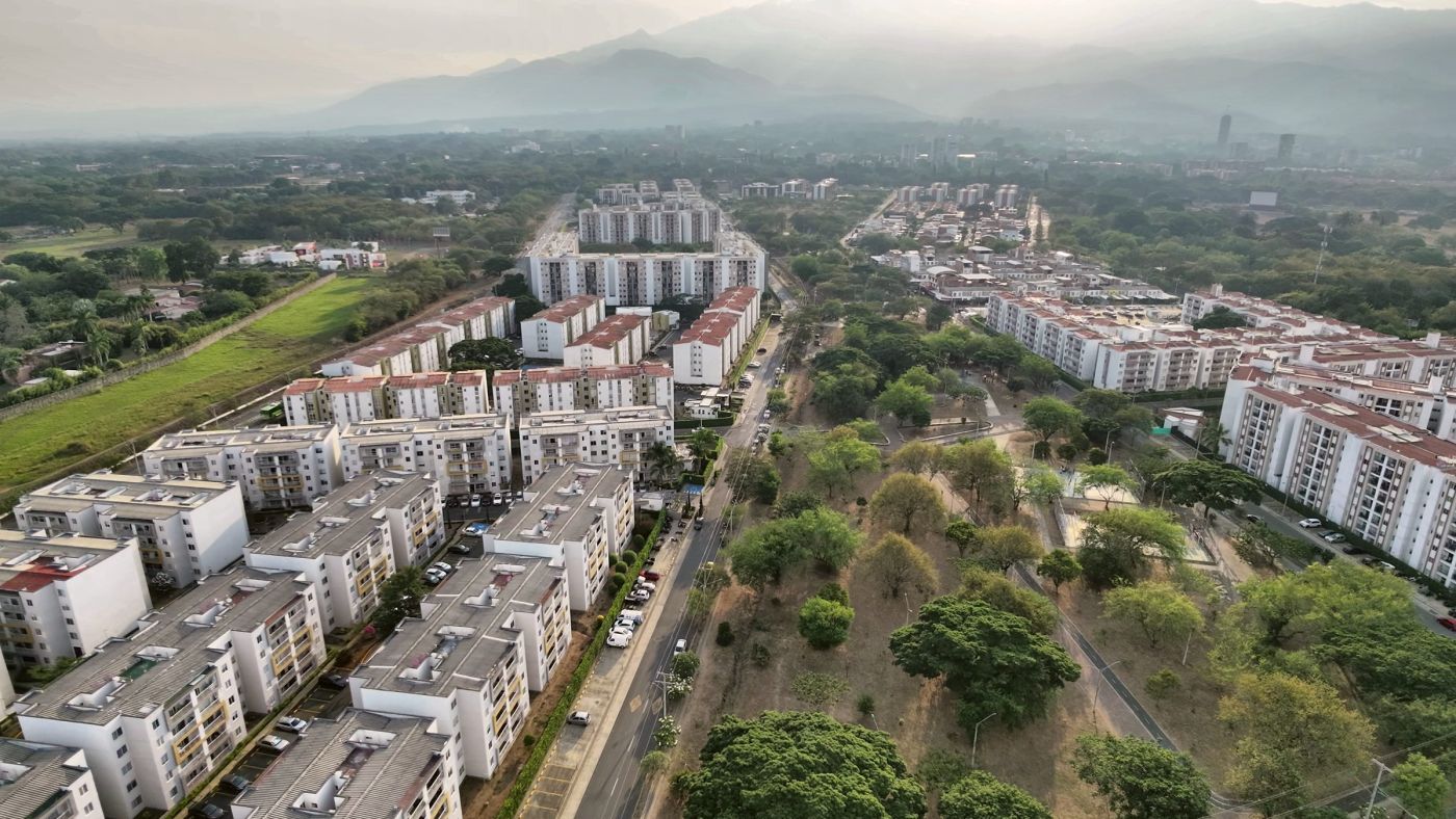 Conjuntos residenciales y zona verde al atardecer con montañas al fondo