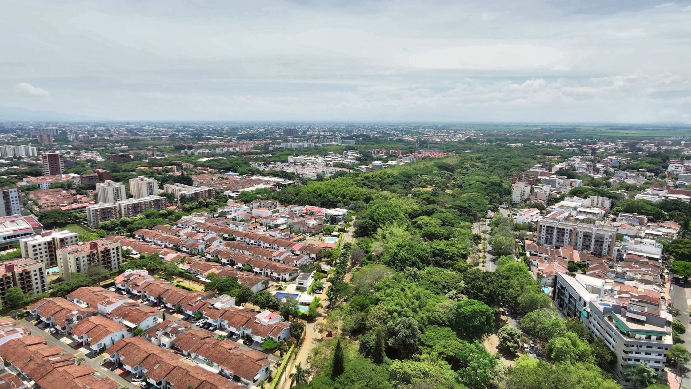 Barrio residencial de techos rojos junto a un corredor de árboles