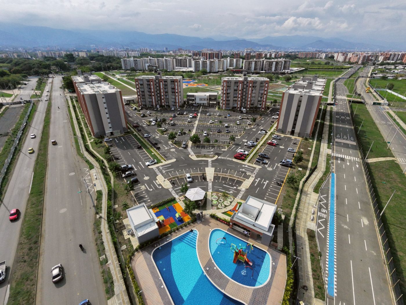 Vista aérea de un conjunto residencial con dos piscinas, zona infantil y torres de apartamentos en Cali